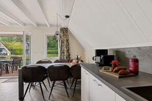 A modern kitchen with a dining area, a coffee maker, and a bottle of juice on the counter. - Holiday apartment with 3 bedrooms (Gramsbergen)