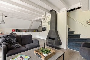 A modern living room with a fireplace, a sofa, a coffee table, and a staircase. - Holiday apartment with 3 bedrooms (Gramsbergen)