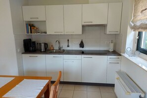 A kitchen with white cabinets, a countertop, a sink, and a window with a view. - Villaparc Duynopgangh House 28 (Julianadorp aan Zee)