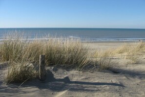 A beach with sand, grass, and a wooden post. - Villaparc Duynopgangh House 28 (Julianadorp aan Zee)