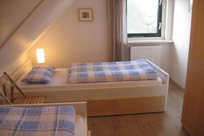 Une petite pièce agréable, dotée d’un lit simple, d’une table de chevet et d’une fenêtre avec des rideaux.