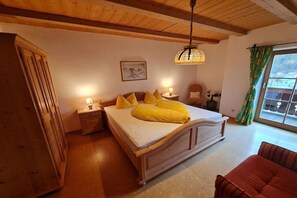 A bedroom with a wooden bed, bedside lamps, a window with curtains, and a painting on the wall. - Lauchlehen - Fewo Göll (Bischofswiesen)