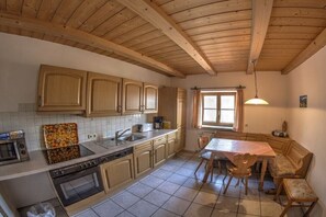 Eine Küche mit Holzausstattung, einem Esstisch, Stühlen, einem Fenster und einer Pendelleuchte.