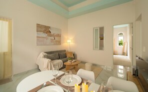 A living room with a sofa, a dining table set for two, a painting on the wall, and a lamp. - Cloud & Mountain Hotel Da Lat (Lam Vien - Da Lat)