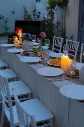 A dining table set with plates, glasses, and candles, surrounded by white chairs. - Cloud & Mountain Hotel Da Lat (Lam Vien - Da Lat)