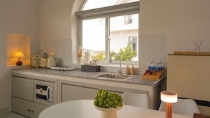 A modern kitchen with a built-in oven, a sink, and a window overlooking a garden.