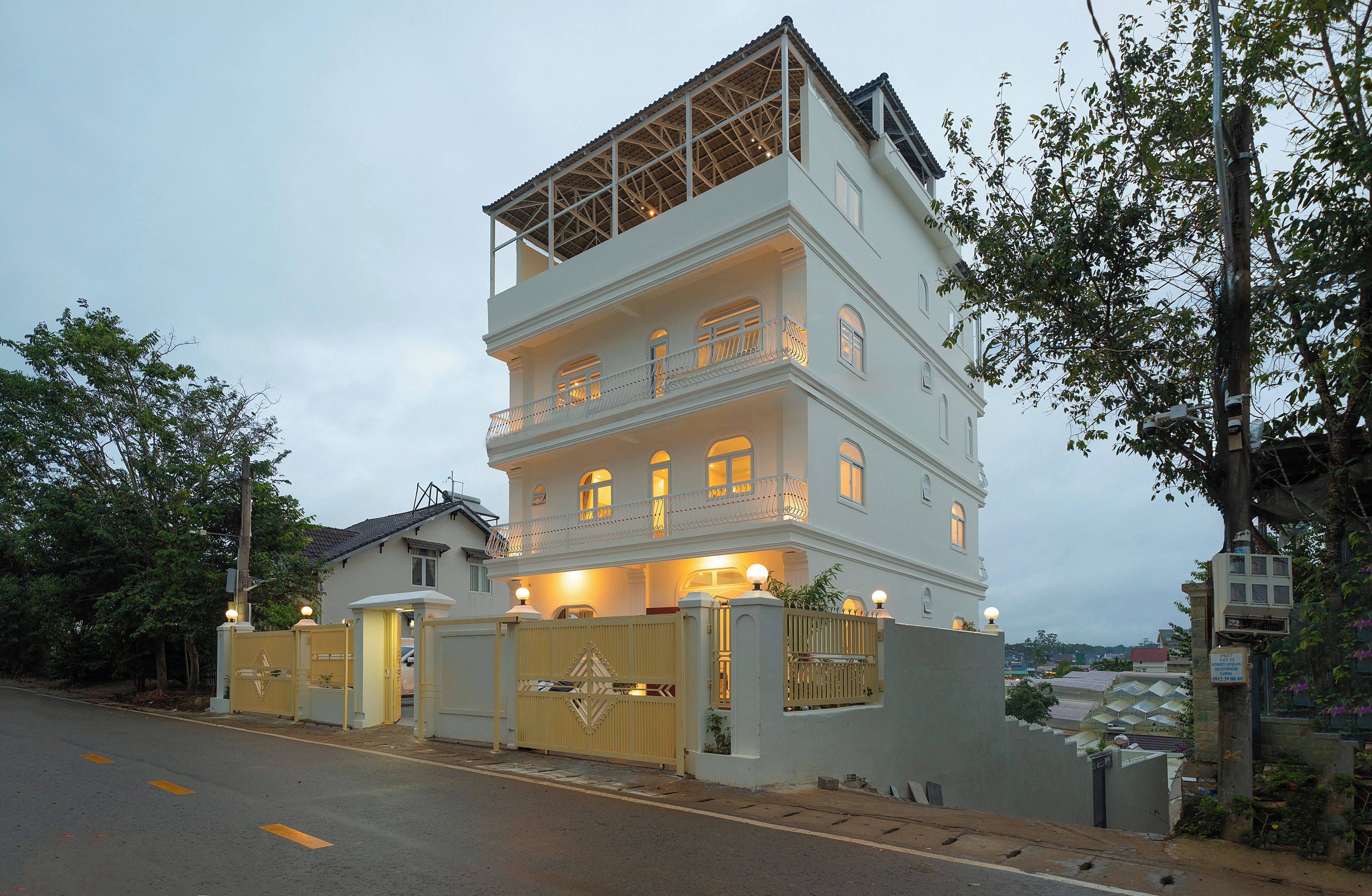 A multi-story building with a gated entrance, a balcony on the upper floor, and a view of the surrounding area.