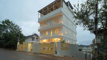 A multi-story building with a gated entrance, a balcony on the upper floor, and a view of the surrounding area.