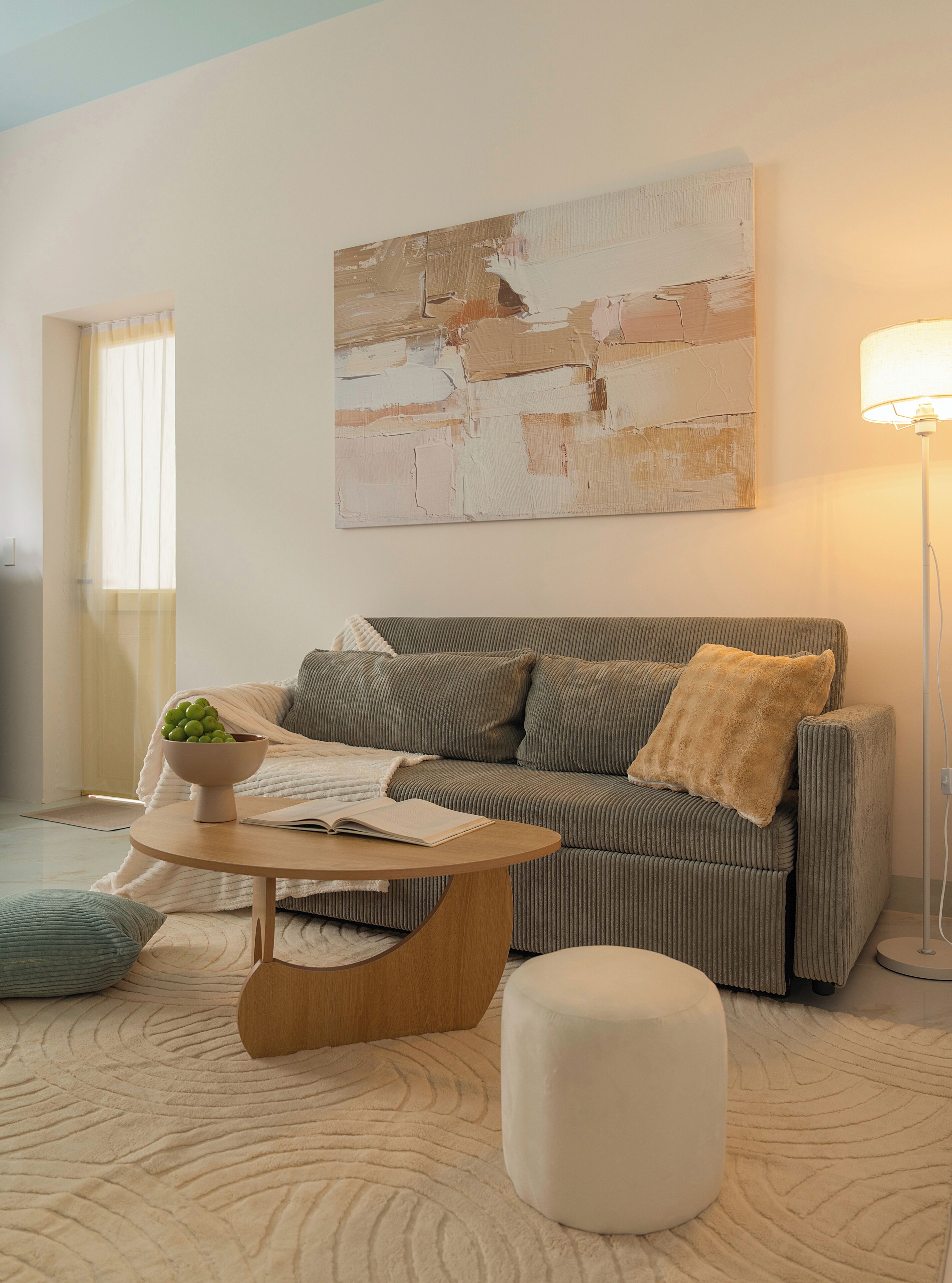 Una sala de estar moderna con un sofá, una mesa de centro, una lámpara y un cuadro en la pared.