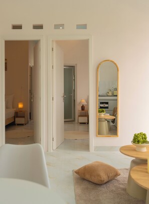 Een moderne hotelkamer met een grote spiegel, een ronde houten tafel en een knus zithoekje met een kussen.