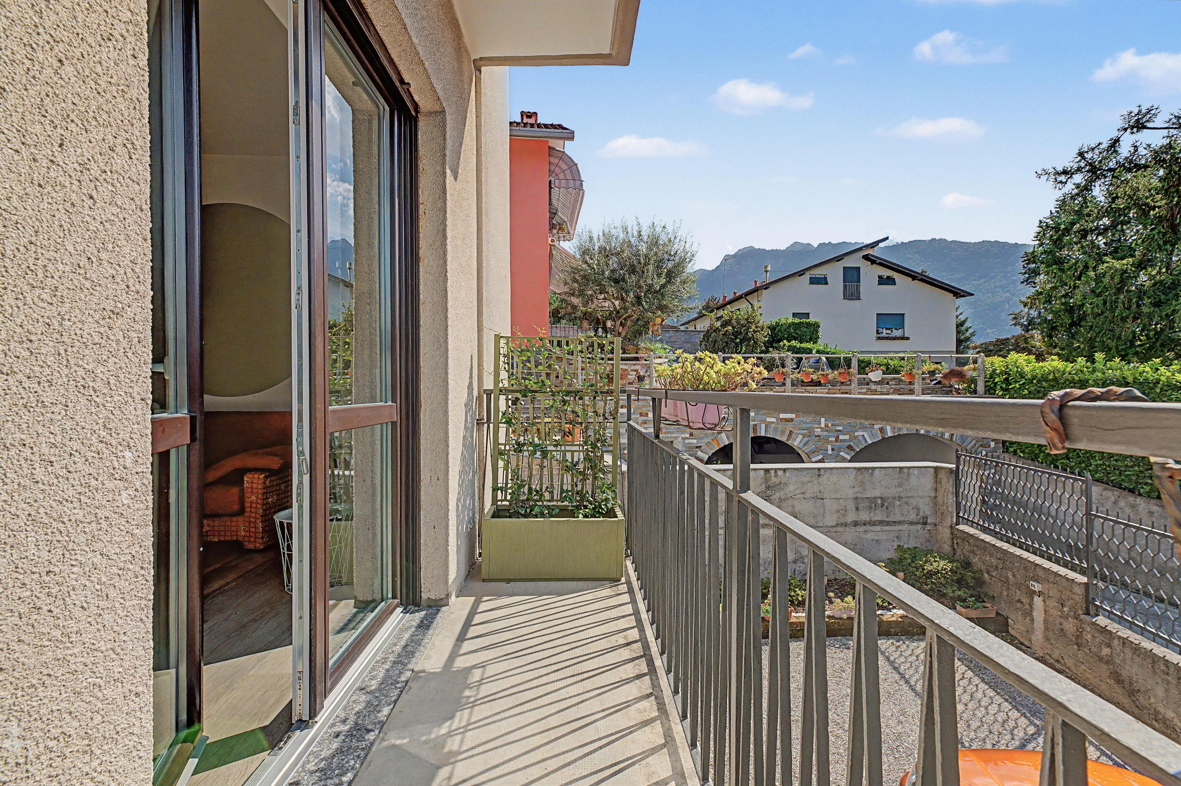 Un balcon avec vue sur une montagne, une maison en arrière-plan et un ciel dégagé.