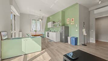 Une cuisine moderne avec des meubles blancs, un coin repas comprenant une table et des chaises, et un espace de vie avec une table noire.