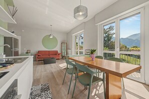 A modern kitchen with a dining area, a red sofa, and a view of the outdoors.
