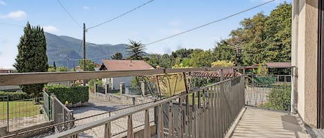 Un balcón con vistas a una montaña, un jardín y un edificio con tejado de tejas.