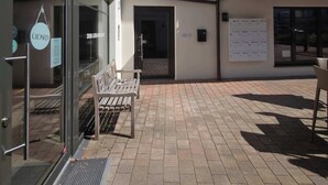 A building with a closed shop entrance, a bench, and a small outdoor seating area.