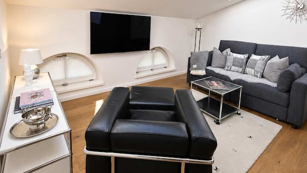 Uma sala de estar moderna com um claraboia, um sofá, uma mesa de centro e uma televisão de tela plana.