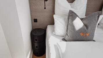 Ein Schlafzimmer mit einem Holzkopfteil, einem Nachttisch und einem bei der Bettseite stehenden Tisch.