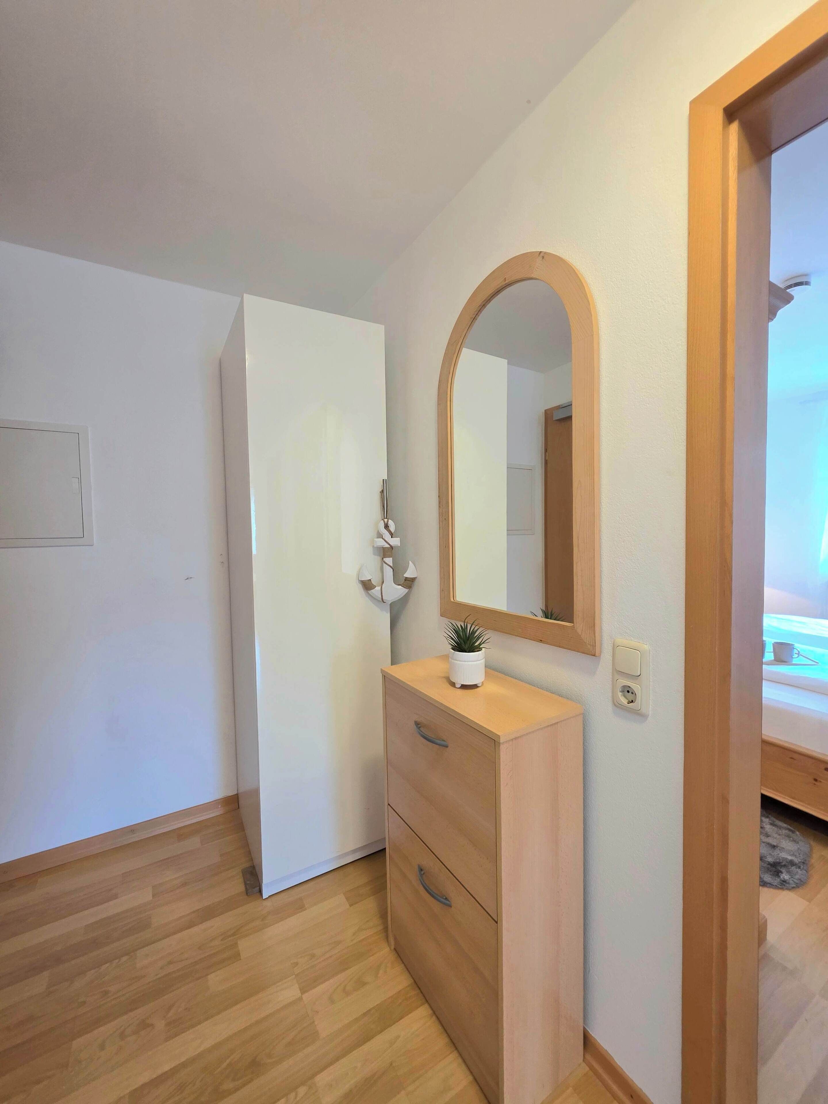 A room with a wooden dresser, a mirror, and a door.