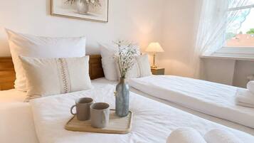 Een hotelkamer met een groot bed, een nachtkastje met een lamp, een lijst aan de muur en een raam met gordijnen.