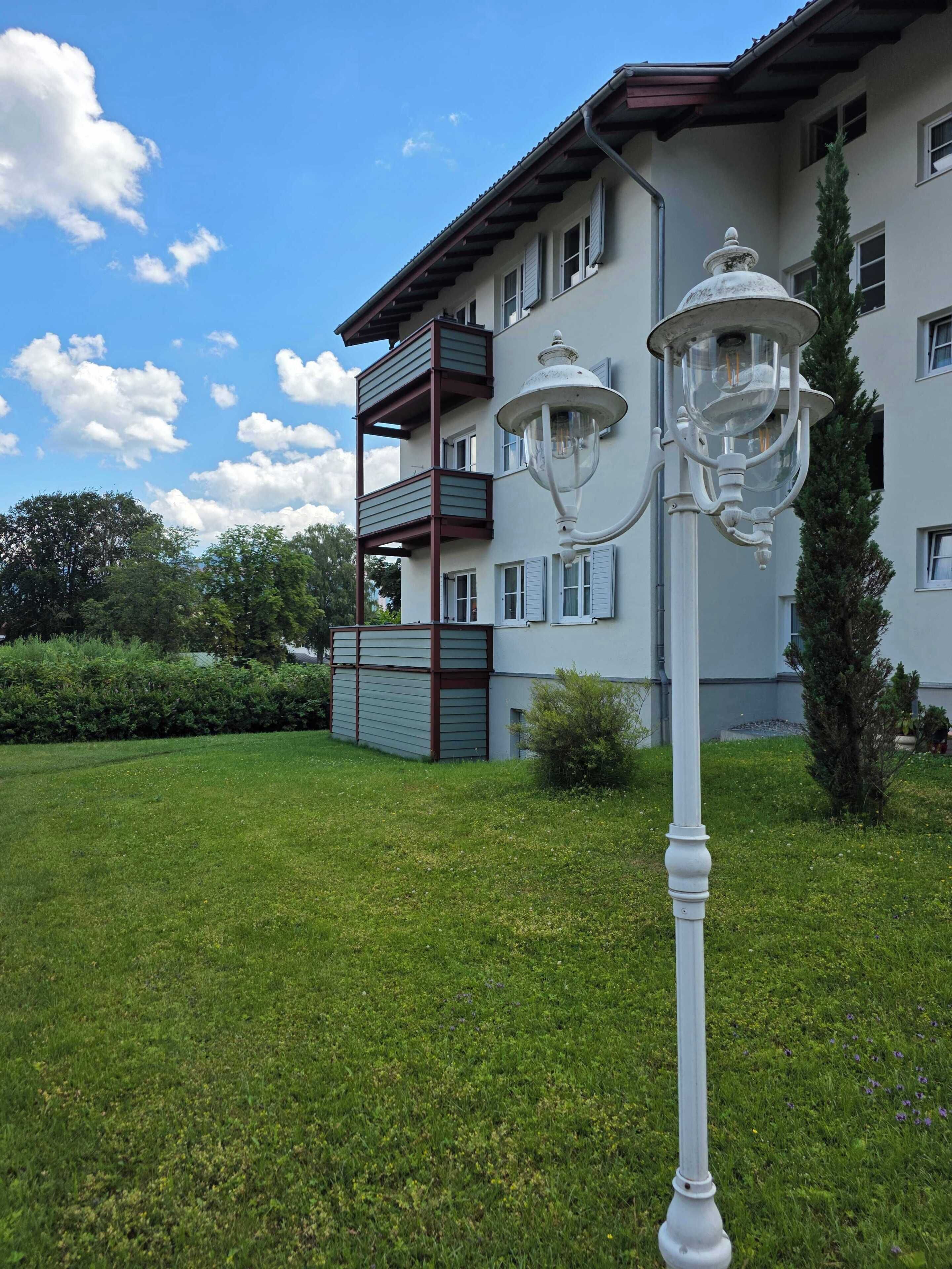 Um edifício com varanda, poste de luz e gramado bem cuidado.