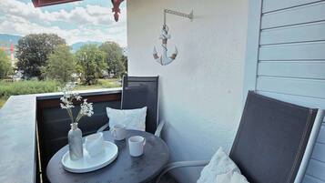 Een balkon met een tafel, stoelen en een decoratief hangend object.