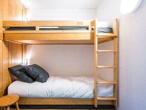 Een stapelbed met een ladder, een klein krukje en een kussen.