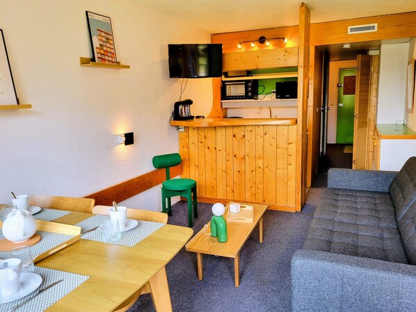 A compact living space with a kitchenette, a seating area with a sofa and chairs, and a dining table with tableware. - Studio cabin - ski-in/ski-out, balcony - 5 guests (Les Arcs 1800)