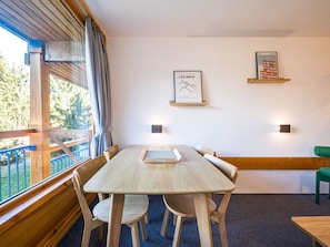 A wooden dining table with chairs, a framed map on the wall, and a view of the outdoors. - Studio cabin - ski-in/ski-out, balcony - 5 guests (Les Arcs 1800)