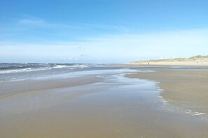 A beach with a wide sandy shore, gentle waves, and a clear sky. - Holiday home with 4 bedrooms (Julianadorp)