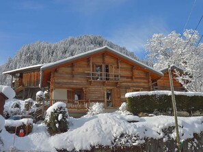 Eine Blockhütte mit Holzfassade, einer Veranda und einer schneebedeckten Landschaft.
