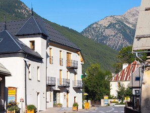 A building with multiple balconies, a mountain backdrop, and a clear sky. - Cozy apartment in the heart of the village - 5 guests (Le Monêtier-les-Bains)