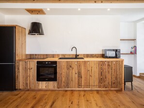Une cuisine moderne avec des meubles en bois, un four encastré, un four à micro-ondes et un robinet noir.