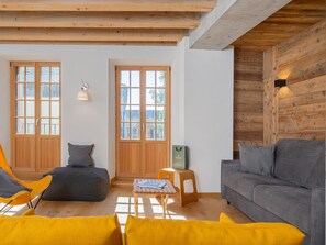 A modern living room with wooden beams, a grey sofa, yellow cushions, and a wooden table with a magazine. - Cozy apartment in the heart of the village - 5 guests (Le Monêtier-les-Bains)