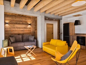 Un salon avec un plafond en bois, un canapé, un fauteuil jaune et une petite table.