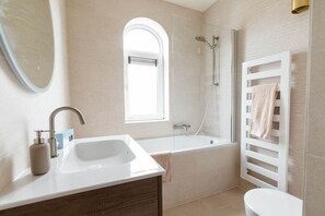 Une salle de bain moderne équipée d’un lavabo, d’un miroir, d’une douche et de toilettes.