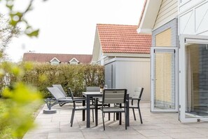Une terrasse extérieure avec une table et des chaises, une bouteille et un verre.