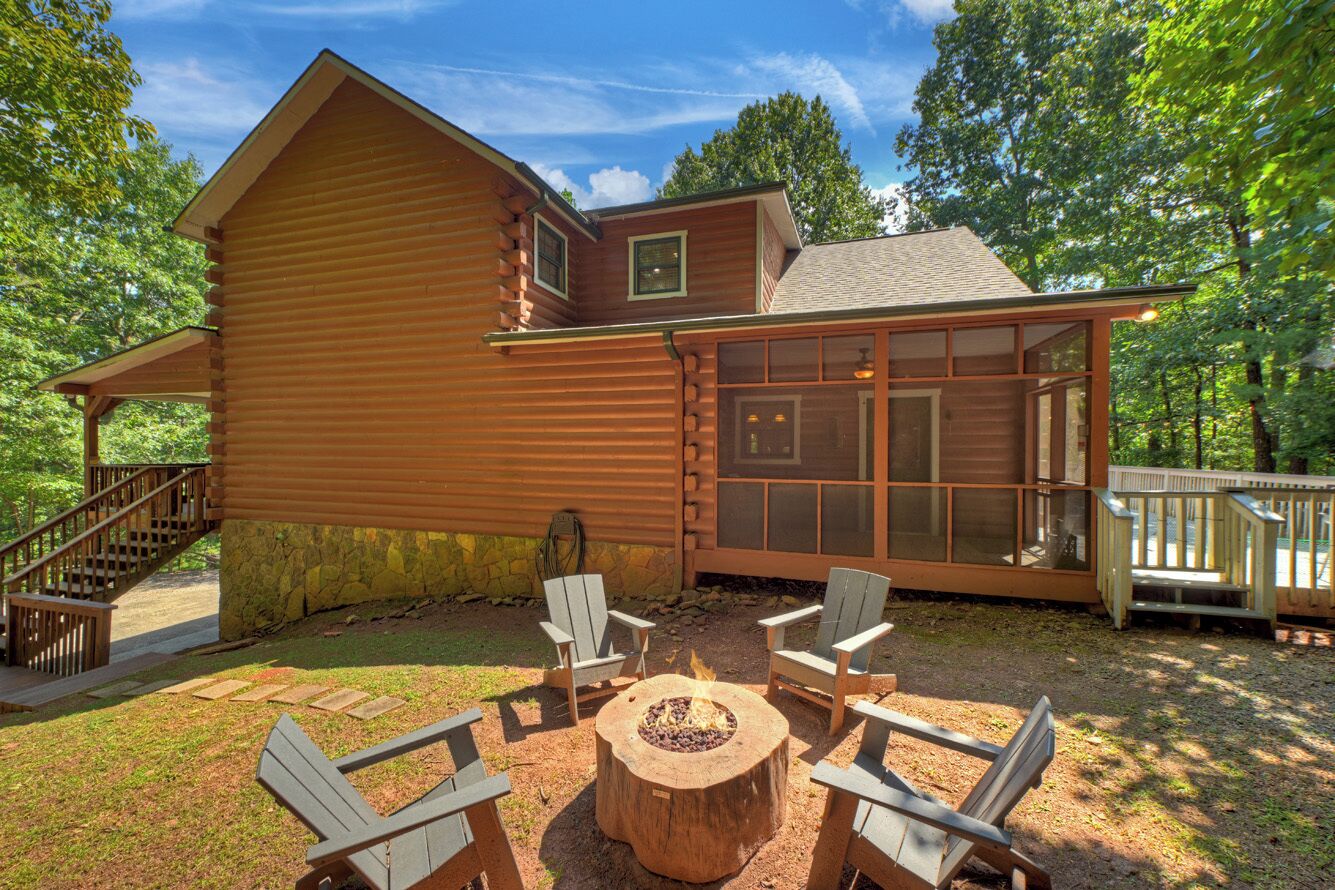 A log cabin with a deck, outdoor seating, and a fire pit.