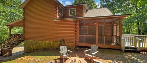 A log cabin with a deck, outdoor seating, and a fire pit.