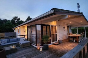 A modern house with a deck, outdoor seating, and a large window. - Cabin in Berkhout with swimming pool (Berkhout)