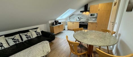 A compact living space with a dining area, kitchenette, and a loft bedroom with a skylight.