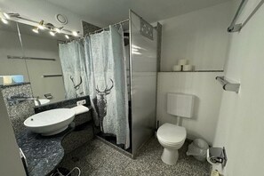 A bathroom with a white sink, toilet, and shower curtain. - No. 16 - Winterhaldenweg 37 (Hinterzarten)