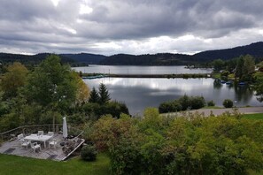 Eine Seeterrasse mit Gartenmöbeln, umgeben von üppiger Vegetation und einem ruhigen See.
