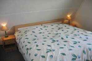 A bedroom with a bed, two bedside lamps, and a wooden headboard. - Holiday home with 3 bedrooms (Julianadorp)