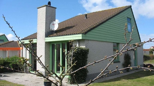 Uma casa térrea com fachada verde e telhado marrom.