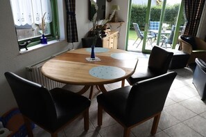 A dining area with a round wooden table, black chairs, and a view through a glass door to an outdoor patio. - Holiday home with 3 bedrooms (Julianadorp)