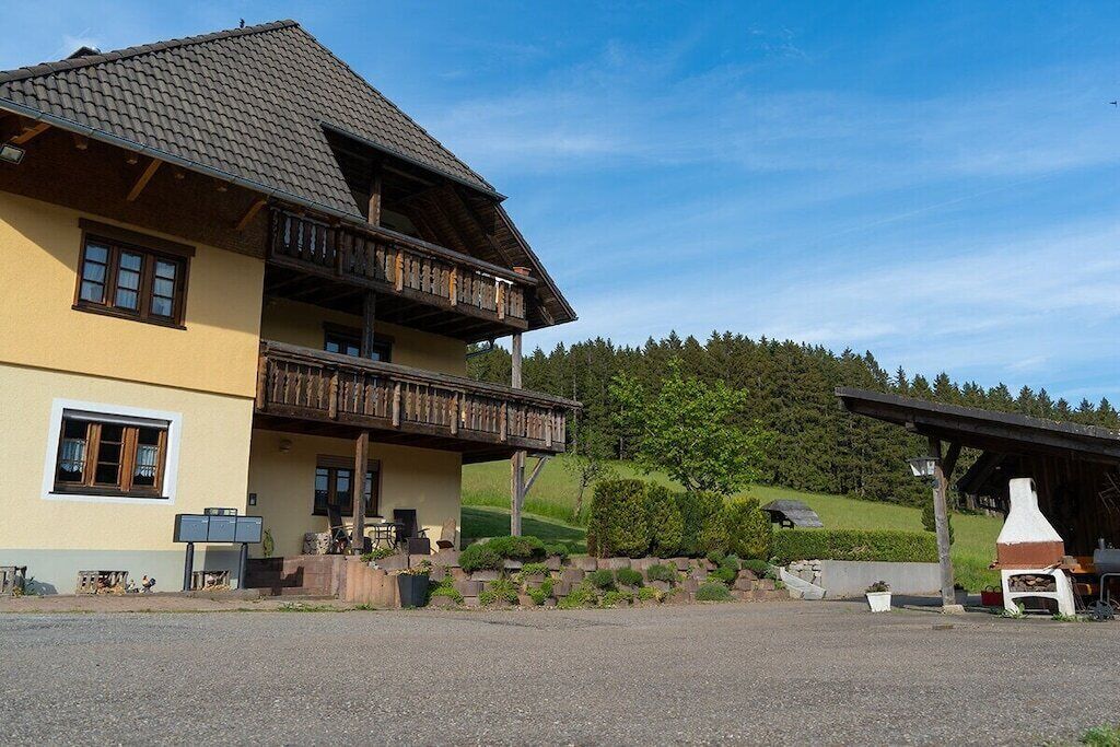 A two-story building with a balcony, a covered outdoor seating area, and a stone fireplace.