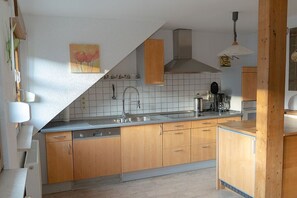 A kitchen with wooden cabinets, a stainless steel sink, and a tiled backsplash. - 2 Kleinklausenhof Farm (Vöhrenbach)