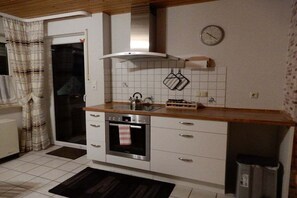 Eine kleine Küche mit Herd, Backofen und einer Uhr an der Wand.