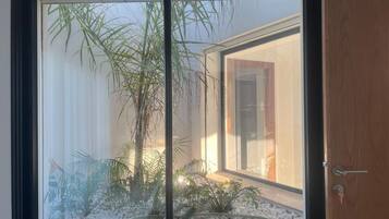 Una habitación con un ventanal grande, una puerta y un pequeño jardín interior.