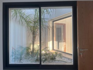 Una habitación con un ventanal grande, una puerta y un pequeño jardín interior.